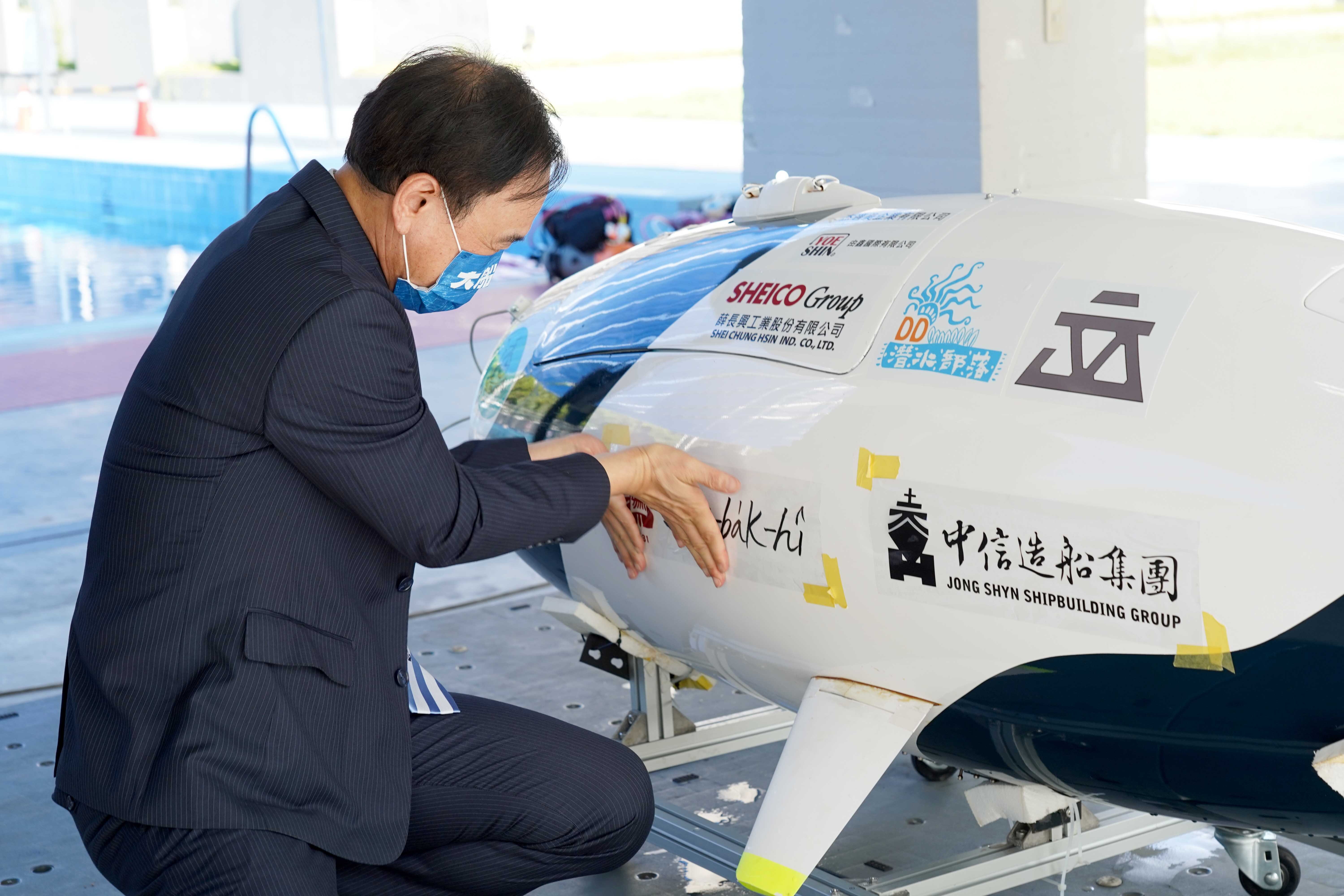 NCKU vice president Fong-Chin Su put the name sticker which wrote by prisident Huey-Jen Su on the human-powered submarine